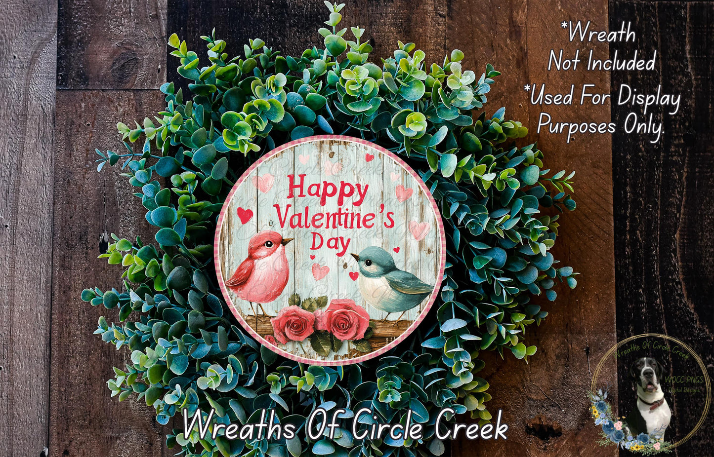 A wreath made of green leaves and flowers, with a circular sign that reads "Happy Valentine's Day" and features illustrations of two birds.