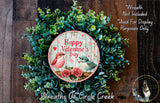 A wreath made of green leaves and flowers, with a circular sign that reads "Happy Valentine's Day" and features illustrations of two birds.