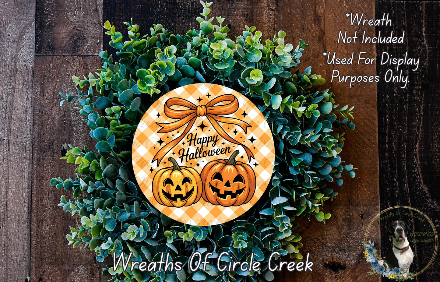 A Halloween wreath made of green foliage and two carved pumpkins, with a text that reads "Happy Halloween" and "Wreath Not Included Used For Display Purposes Only".