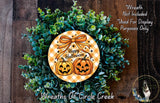 A Halloween wreath made of green foliage and two carved pumpkins, with a text that reads "Happy Halloween" and "Wreath Not Included Used For Display Purposes Only".