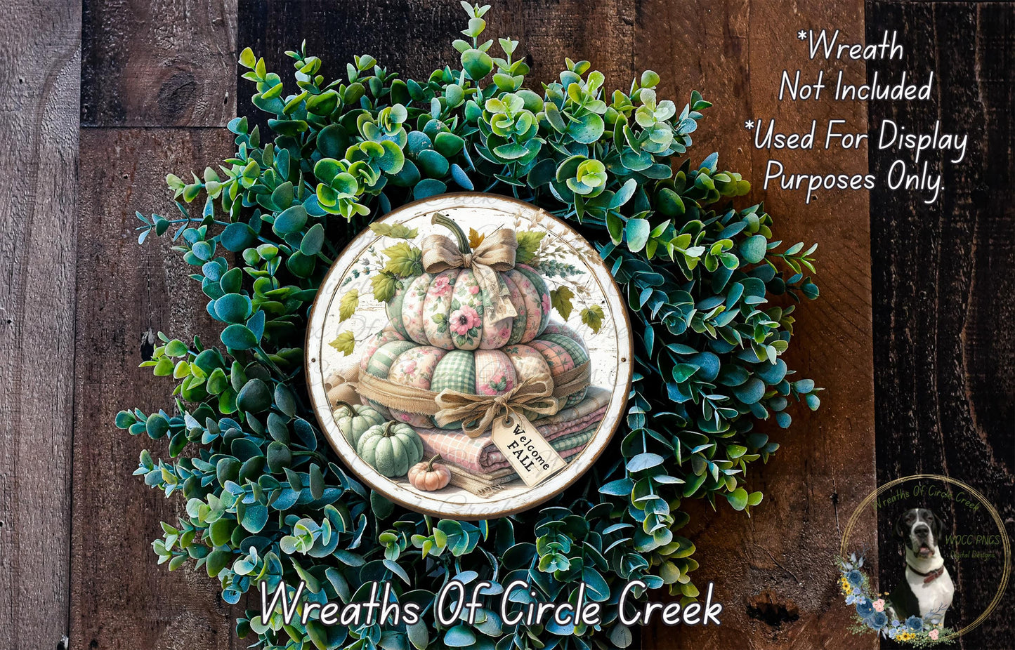 a wreath made of various green plants and a decorative plate with a pumpkin and other fall-themed items. The wreath is displayed on a wooden surface, and the plate is placed on the wreath.