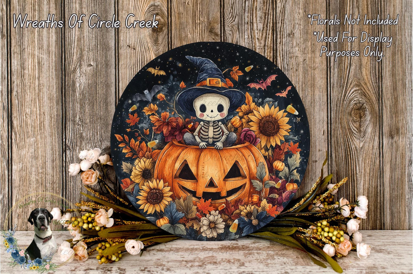 A Halloween-themed wreath featuring a skeleton in a witch's hat sitting on a carved pumpkin surrounded by autumn leaves, sunflowers, and other seasonal decorations.