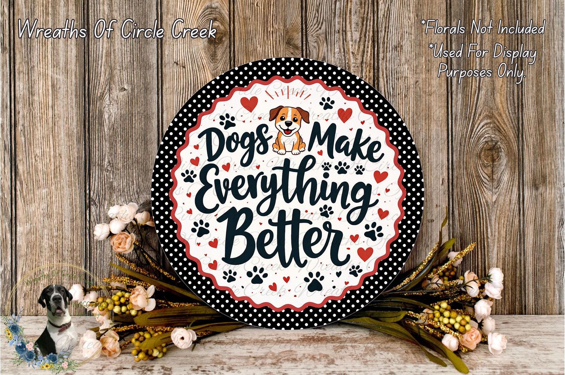 A decorative sign with the text "Dogs Make Everything Better" surrounded by paw prints and flowers, placed on a wooden surface.