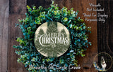 a Christmas wreath made of various green plants, including eucalyptus and other foliage, arranged around a circular design with the text "Merry Christmas" and "Wreaths of Circle Creek".