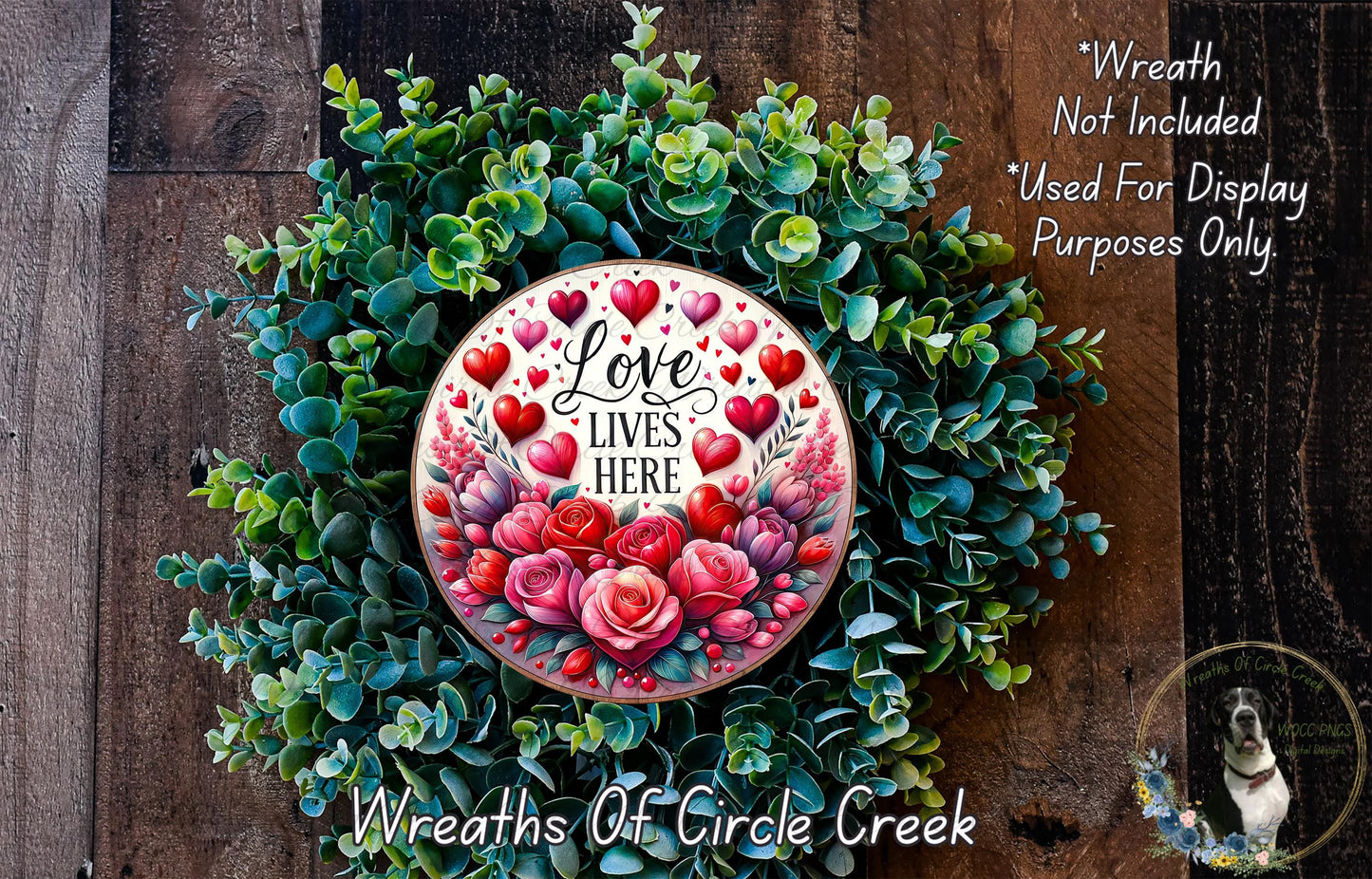A wreath made of green leaves and red roses, with a white circular plaque featuring the text "Love Lives Here" surrounded by red hearts.