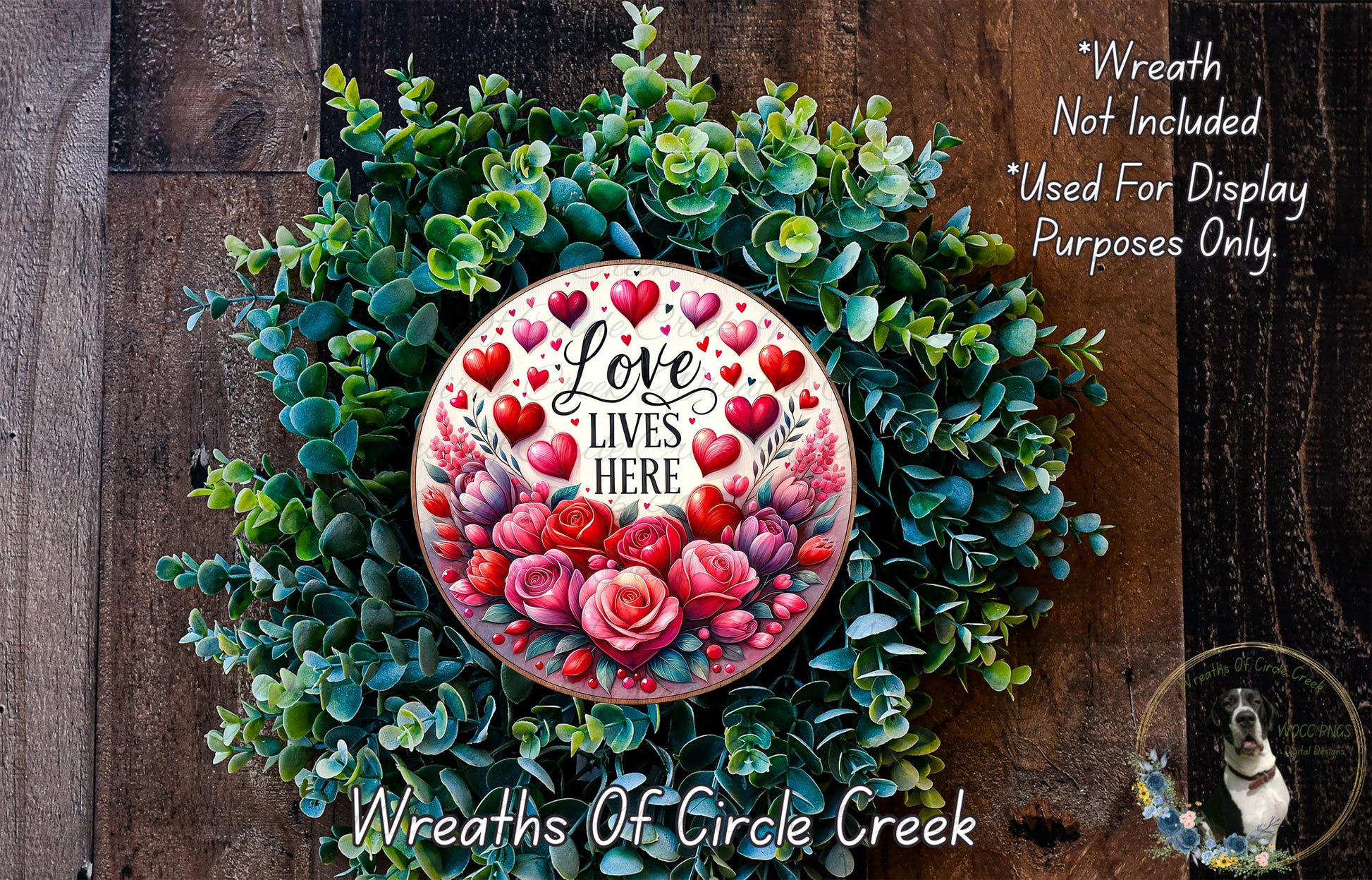 A wreath made of green leaves and red roses, with a white circular plaque featuring the text "Love Lives Here" surrounded by red hearts.
