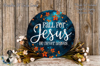 a circular sign with the text "Fall for Jesus he never leaves" surrounded by a floral arrangement and a wooden background.