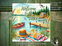 The image is a vibrant and colorful illustration of a lakeside scene, featuring a wooden cabin, a dock, a boat, a straw hat, sunglasses, and a drink. The text "Welcome to the Lake" is prominently displayed, along with the phrase "Wreaths of Circle Creek".