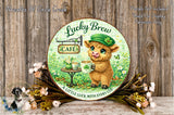 A round sign featuring a cartoon cow holding a cup of Lucky Brew, surrounded by flowers and greenery, with a sign that reads "Lucky Brew CAFE A little luck with every cup".