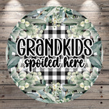 A circular sign with a floral design and the text "GRANDKIDS spoiled here" written in a decorative font.