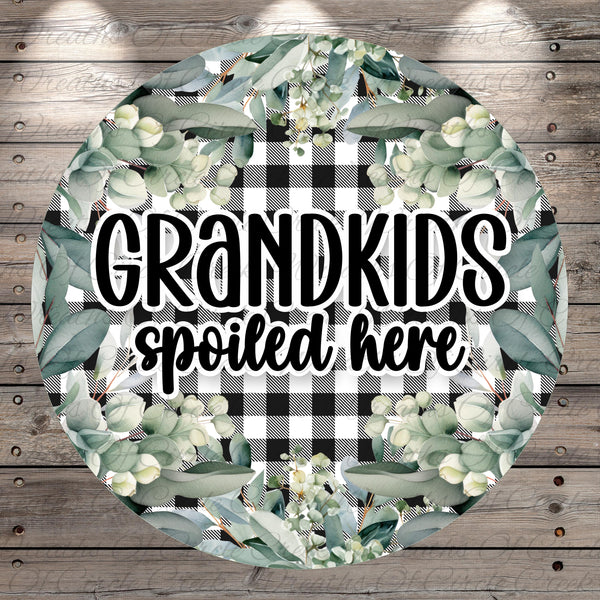 A circular sign with a floral design and the text "GRANDKIDS spoiled here" written in a decorative font.