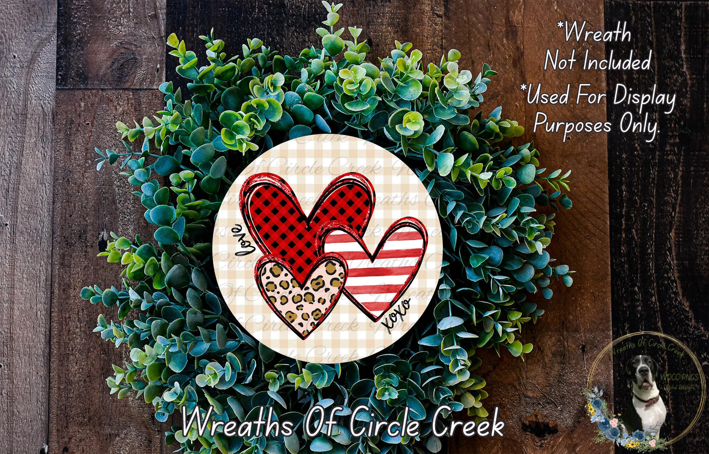 A wreath made of green leaves and two heart-shaped cutouts, one with a red and black checkered pattern and the other with a leopard print pattern.
