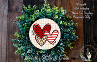 A wreath made of green leaves and two heart-shaped cutouts, one with a red and black checkered pattern and the other with a leopard print pattern.