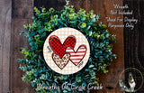 A wreath made of green leaves and two heart-shaped cutouts, one with a red and black checkered pattern and the other with a leopard print pattern.