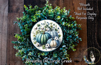 a wreath made of various green plants and pumpkins, with a central design of pumpkins and greenery.
