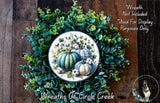 a wreath made of various green plants and pumpkins, with a central design of pumpkins and greenery.