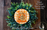 A wreath made of green leaves and a pumpkin, with a teapot and fall-themed decorations, including a "Hello Fall" sign.
