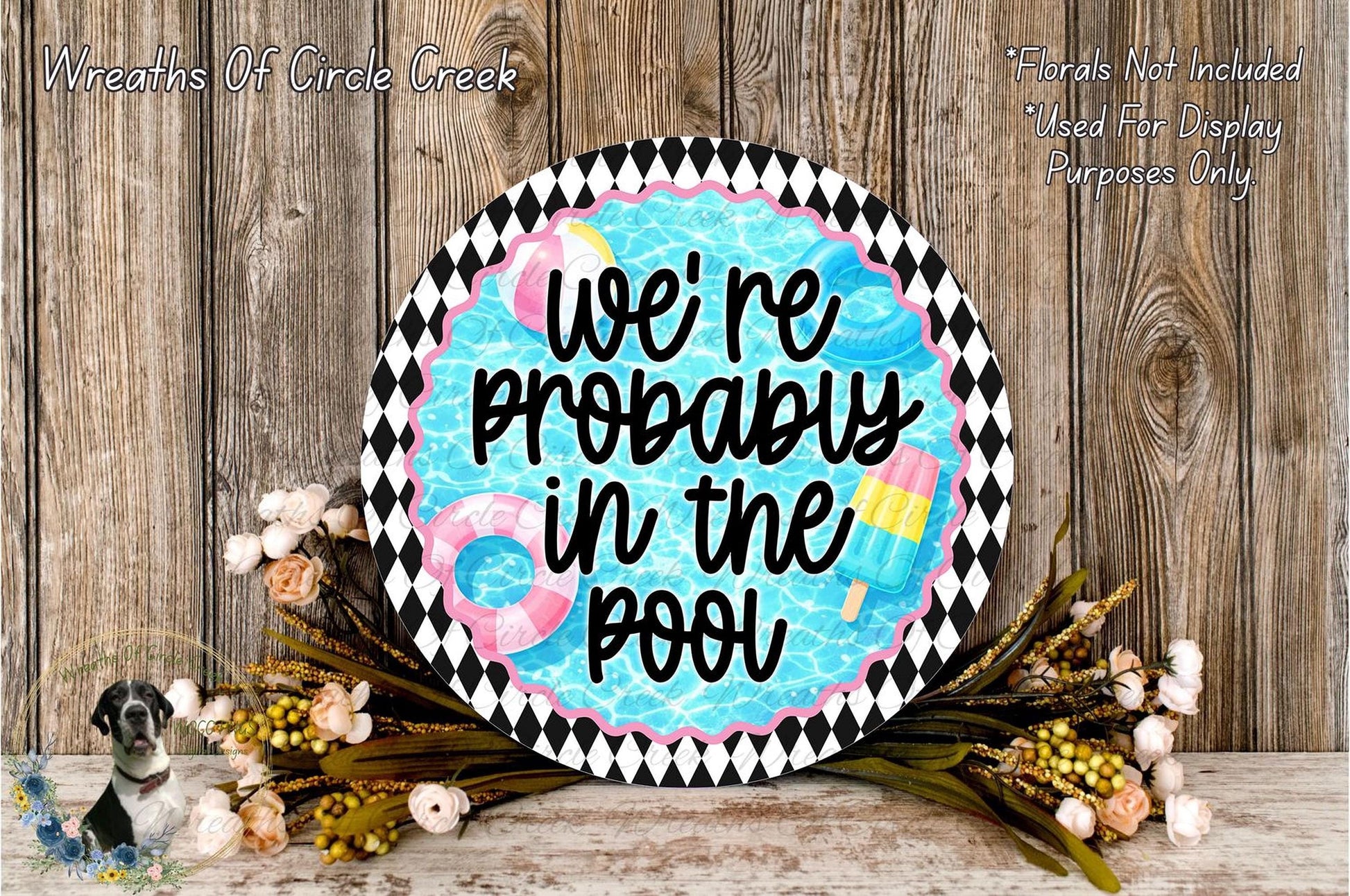 a decorative sign with the text "We're probably in the pool" surrounded by a floral arrangement and a wooden background.