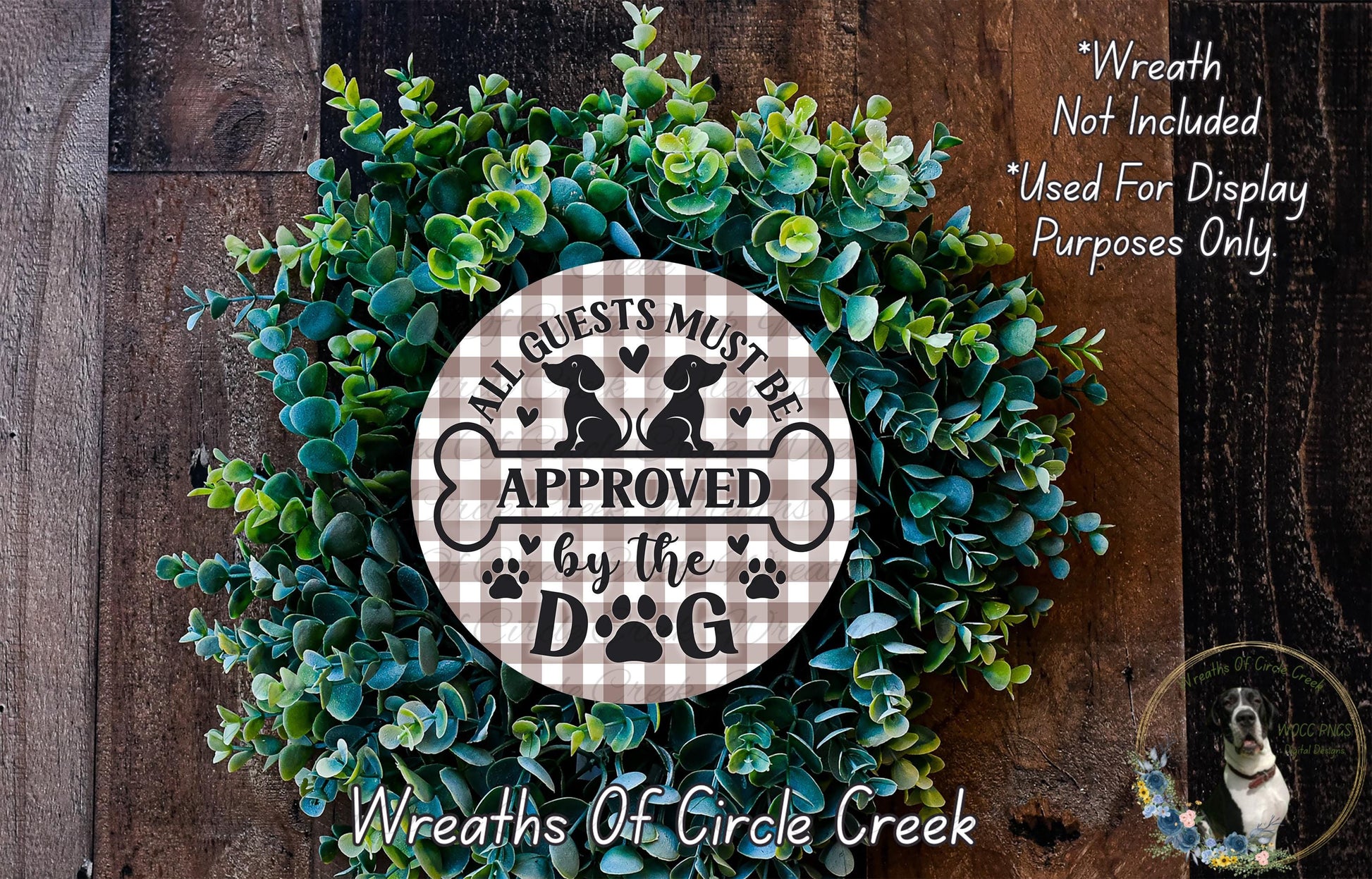 a wreath made of green leaves and a circular sign with the text "All guests must be approved by the dog" on it.