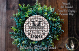 a wreath made of green leaves and a circular sign with the text "All guests must be approved by the dog" on it.
