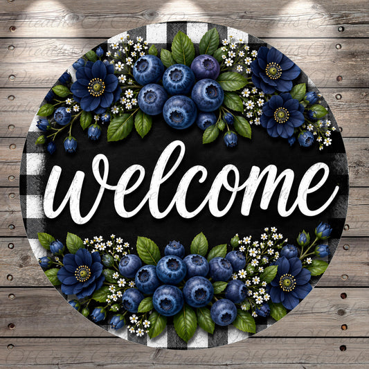 A circular welcome sign with a black background and white text, surrounded by blue flowers and leaves.