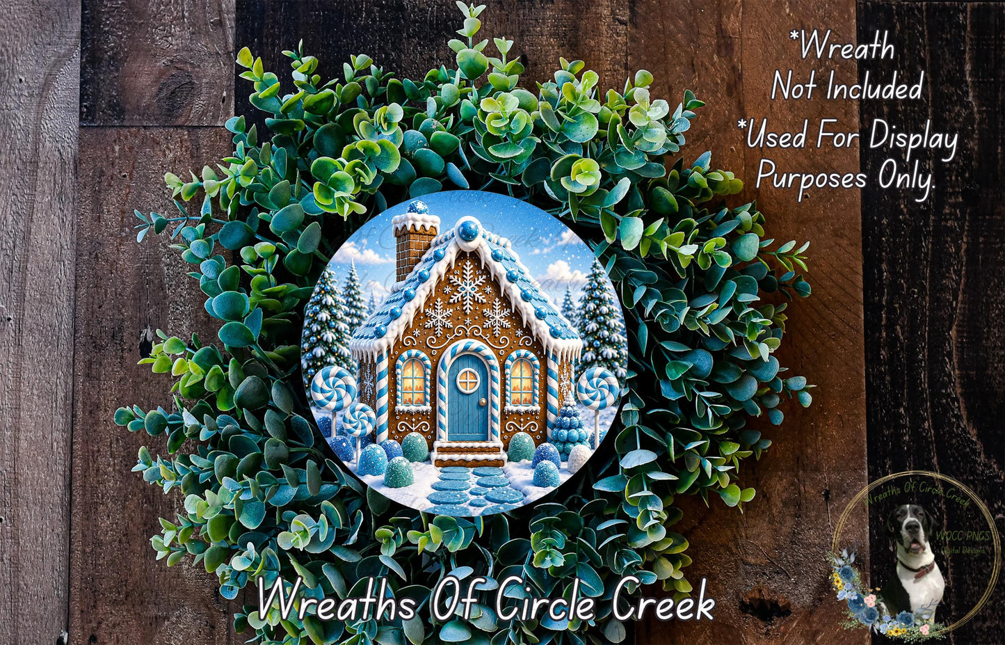 A wreath made of green leaves and a gingerbread house with a snowy roof, placed on a wooden surface.