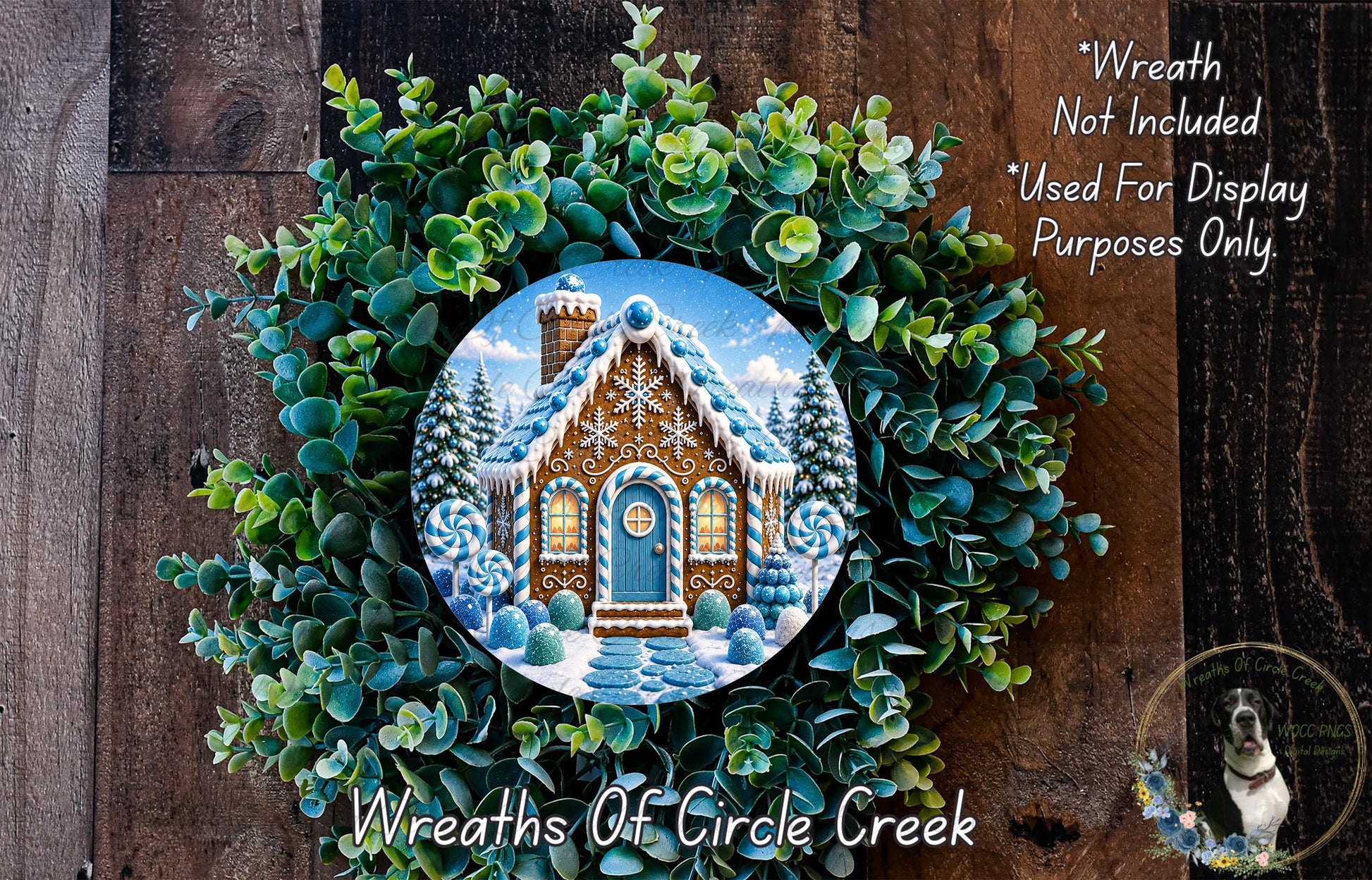 A wreath made of green leaves and a gingerbread house with a snowy roof, placed on a wooden surface.