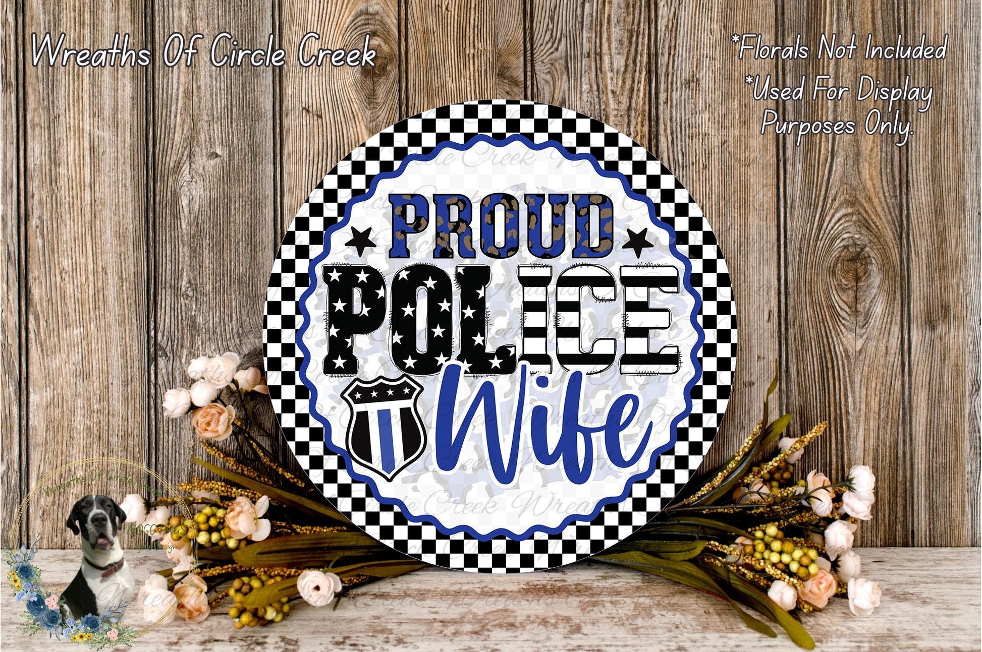 A decorative sign with the text "PROUD POLICE WIFE" displayed prominently, surrounded by a floral arrangement and a wooden background.
