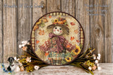 a decorative wreath with a scarecrow design, surrounded by autumn-themed flowers and foliage. The wreath is placed on a wooden surface, and there is a text overlay that reads "Autumn Blessings" and "Wreaths Of Circle Creek".