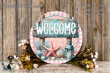 a circular sign with the word "WELCOME" written on it, surrounded by a floral arrangement and a lantern. The sign is placed on a wooden surface, and there are flowers and a lantern nearby.