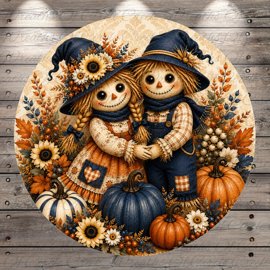 A round, decorative image featuring two scarecrow dolls, one with a blue hat and the other with a yellow hat, surrounded by autumn-themed elements such as pumpkins, flowers, and leaves.