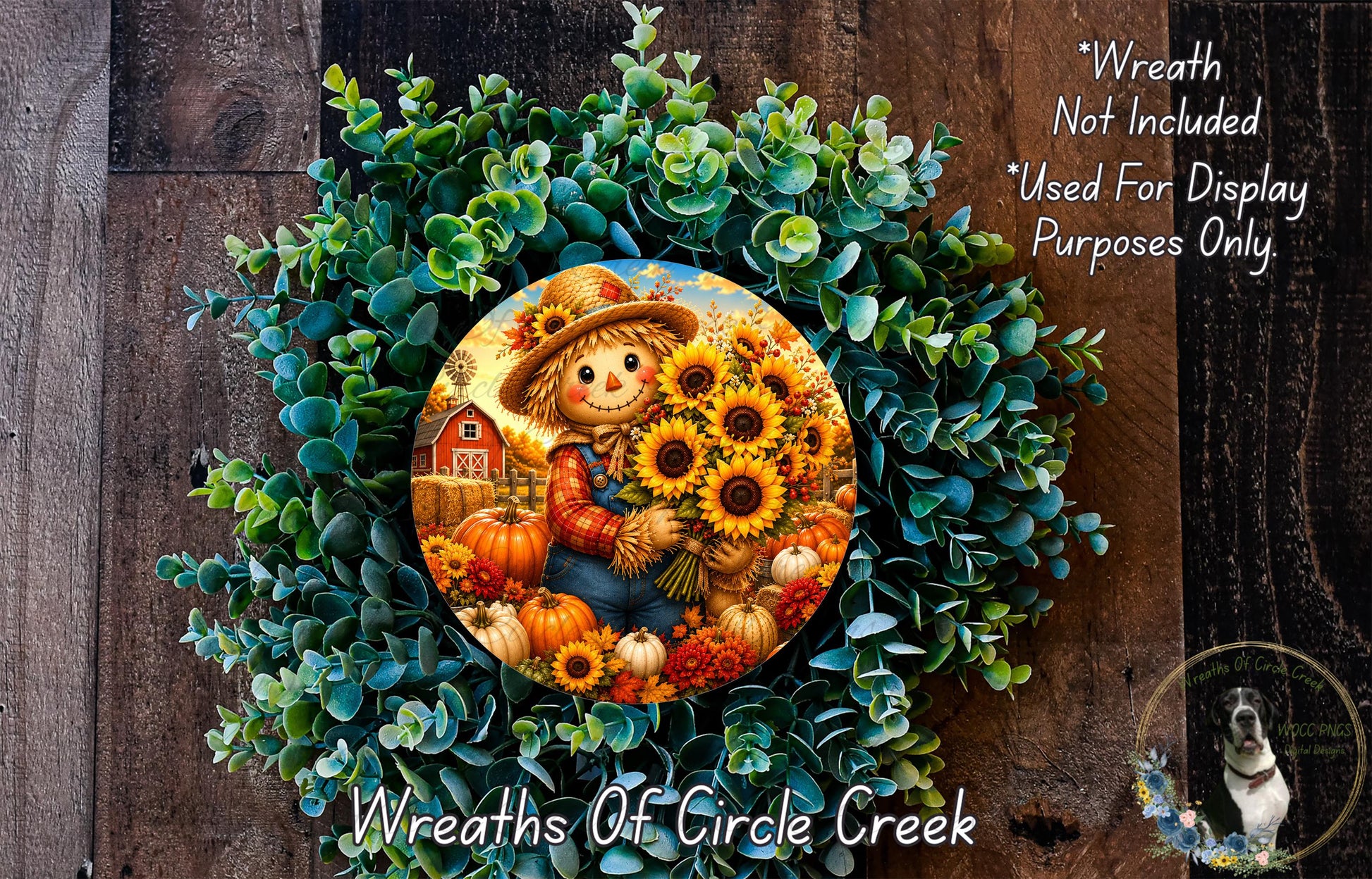 a wreath with a scarecrow and sunflowers, surrounded by greenery. The wreath is displayed on a wooden surface, and there is a small dog in the bottom right corner.