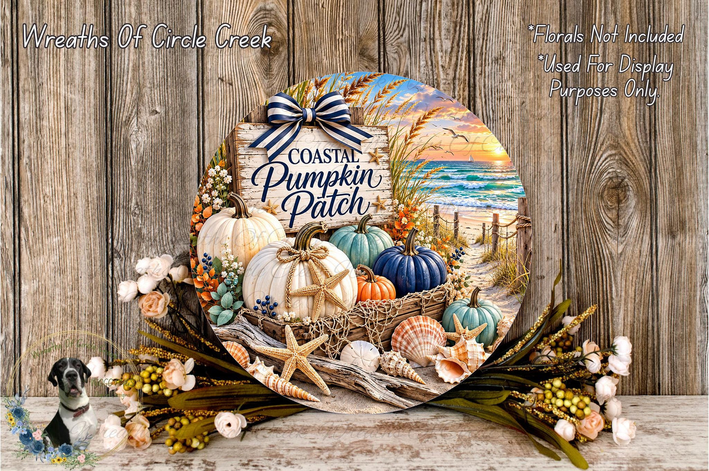 A decorative wreath with a coastal theme, featuring pumpkins, seashells, and a sunset scene. The wreath is displayed on a wooden surface, surrounded by flowers and a small bird figurine.