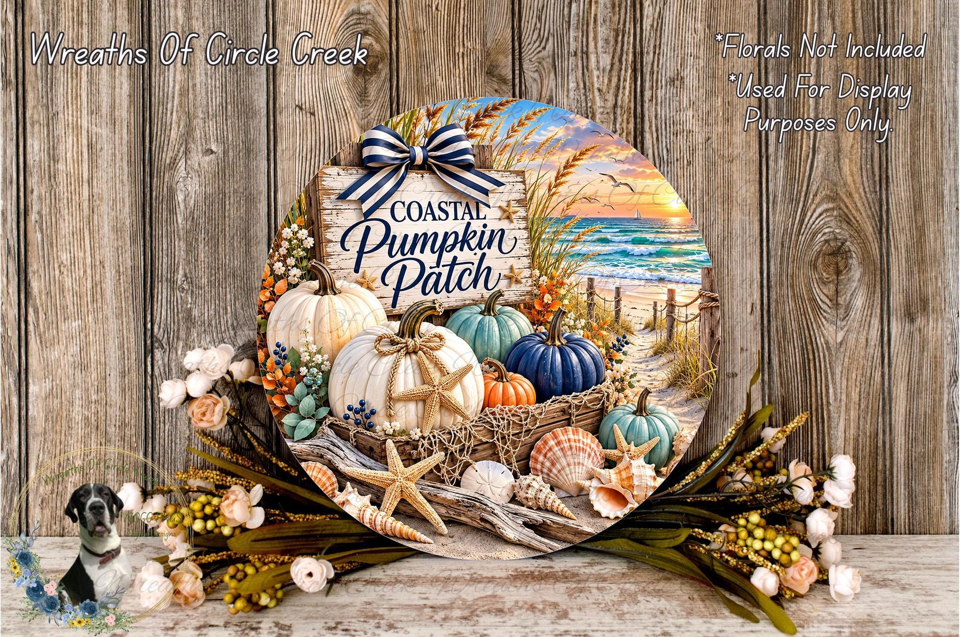 A decorative wreath with a coastal theme, featuring pumpkins, seashells, and a sunset scene. The wreath is displayed on a wooden surface, surrounded by flowers and a small bird figurine.