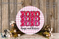a round sign with the text "XOXO XOXO XOXO hugs and kisses" written on it, surrounded by a floral arrangement and a wooden background.