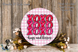 a round sign with the text "XOXO XOXO XOXO hugs and kisses" written on it, surrounded by a floral arrangement and a wooden background.