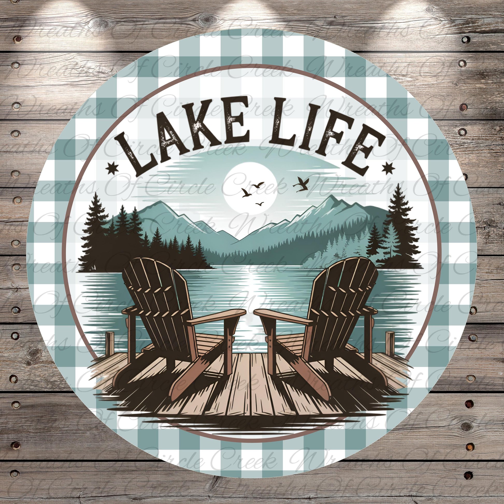 A circular design featuring a lake with a wooden dock and two Adirondack chairs, surrounded by mountains and pine trees. The text "LAKELIFE" is prominently displayed above the chairs.