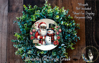 A wreath made of evergreen branches and featuring a Santa Claus and a snowman, with a sign that says "Merry Christmas".