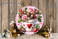 A decorative arrangement featuring a white bucket with a red heart and heart-shaped chocolate-covered strawberries, surrounded by a floral arrangement and a wooden background.