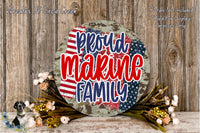 a patriotic-themed wreath with the text "Proud Marine Family" displayed prominently. The wreath is surrounded by a floral arrangement and is set against a rustic wooden background.