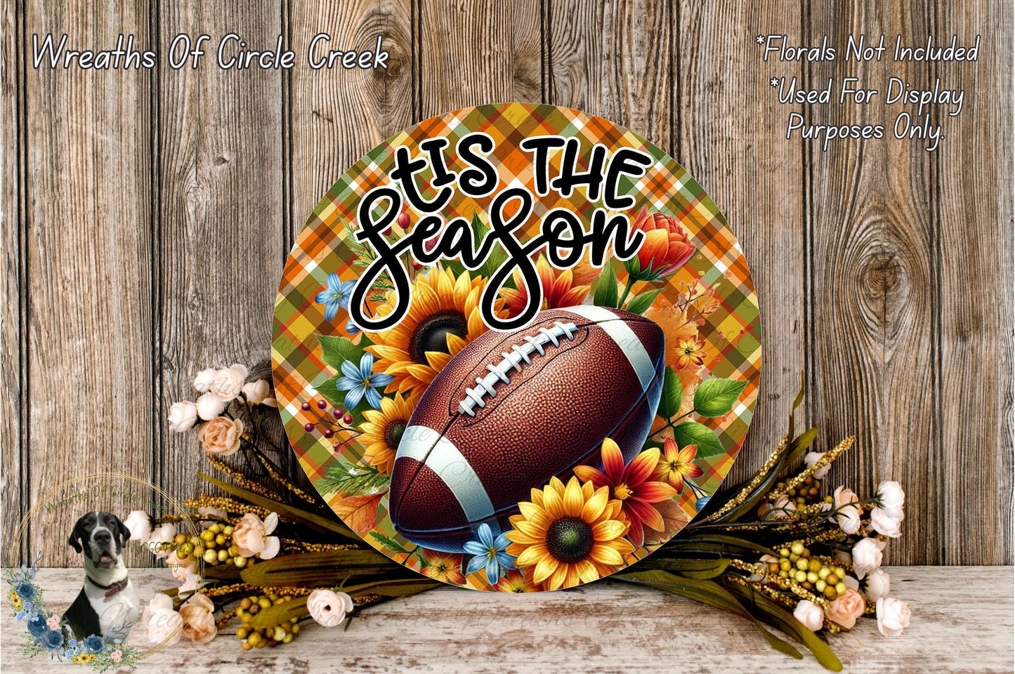 A decorative wreath with a football and sunflowers, along with some flowers and greenery, placed on a wooden surface.