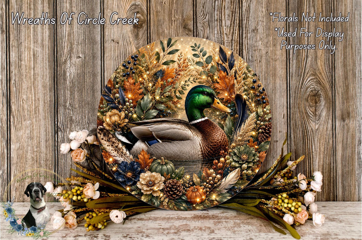 A decorative wreath featuring a duck surrounded by autumn foliage, flowers, and pine cones, displayed on a wooden surface.