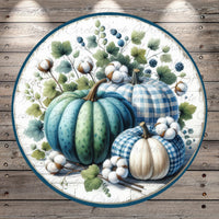 A circular arrangement of three pumpkins, each with a distinct pattern, surrounded by cotton bolls and leaves, set against a wooden background.