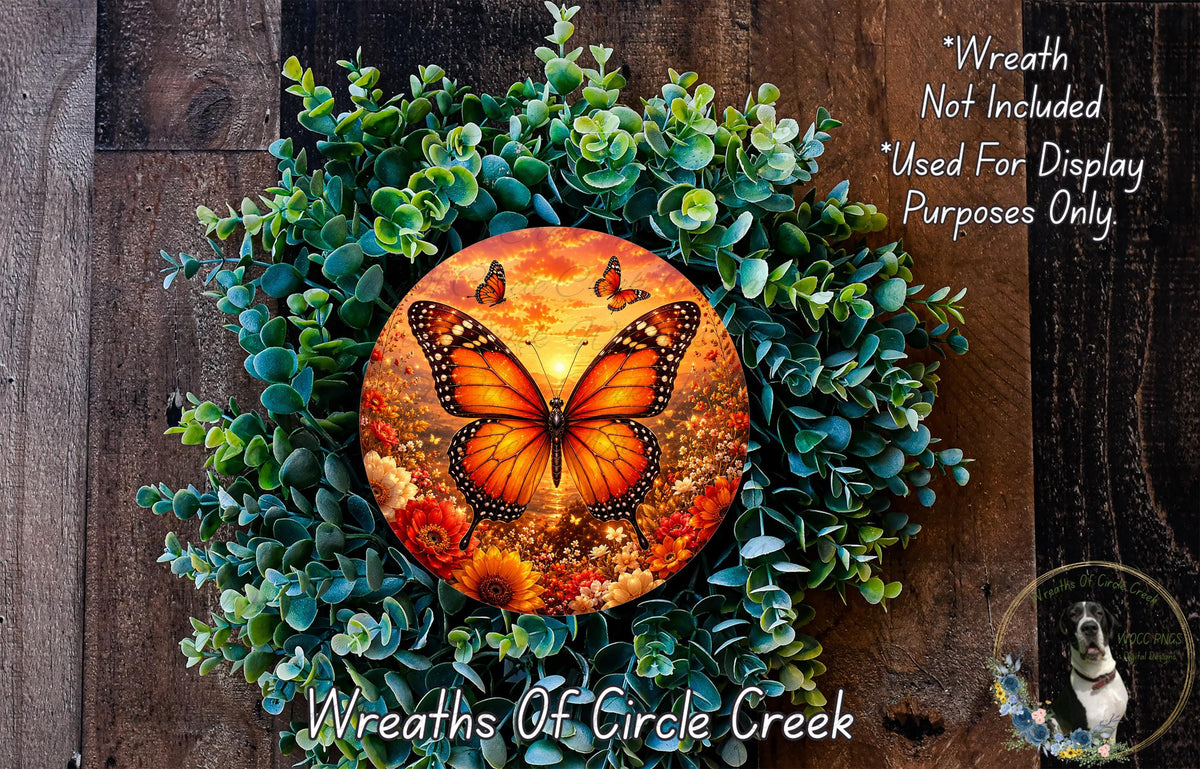 A wreath made of green foliage and flowers, with a large orange butterfly in the center. The wreath is displayed on a wooden surface, and there is a small dog in the bottom right corner.