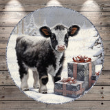 A black and white cow stands in a snowy landscape, surrounded by three gift boxes with red bows, creating a festive scene.