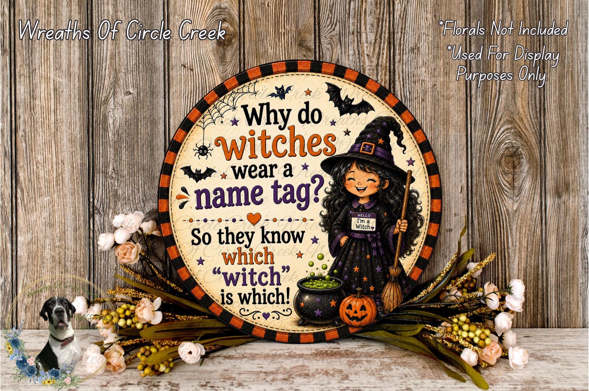 A Halloween-themed sign with a witch and a pumpkin, surrounded by flowers and a wooden background.