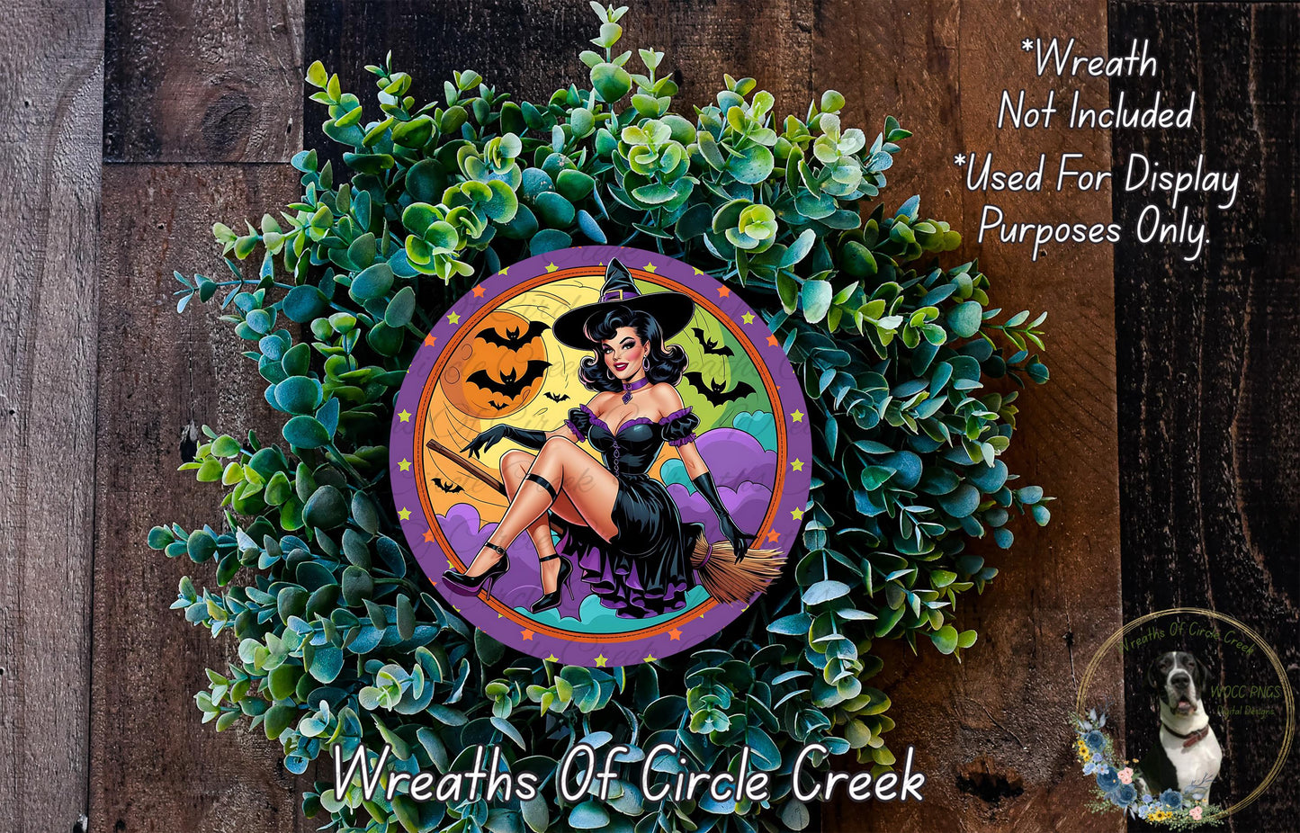 A wreath featuring a woman in a witch's hat, surrounded by green foliage and a colorful design.