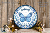 a round blue and white sign with a butterfly design, surrounded by flowers and placed on a wooden surface.