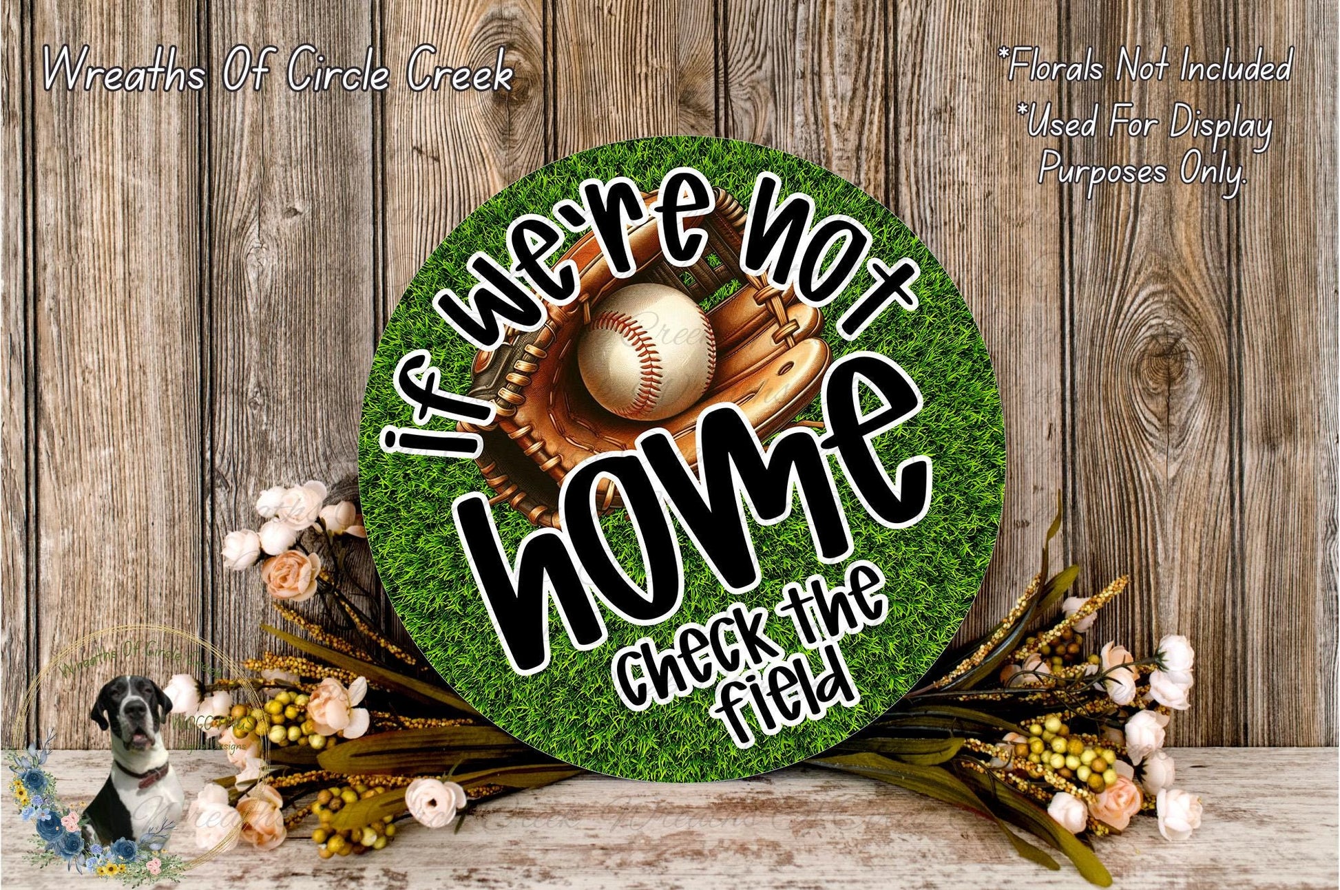a round sign with the text "If we're not home, check the field" on it, surrounded by a baseball glove and ball, and a floral arrangement.