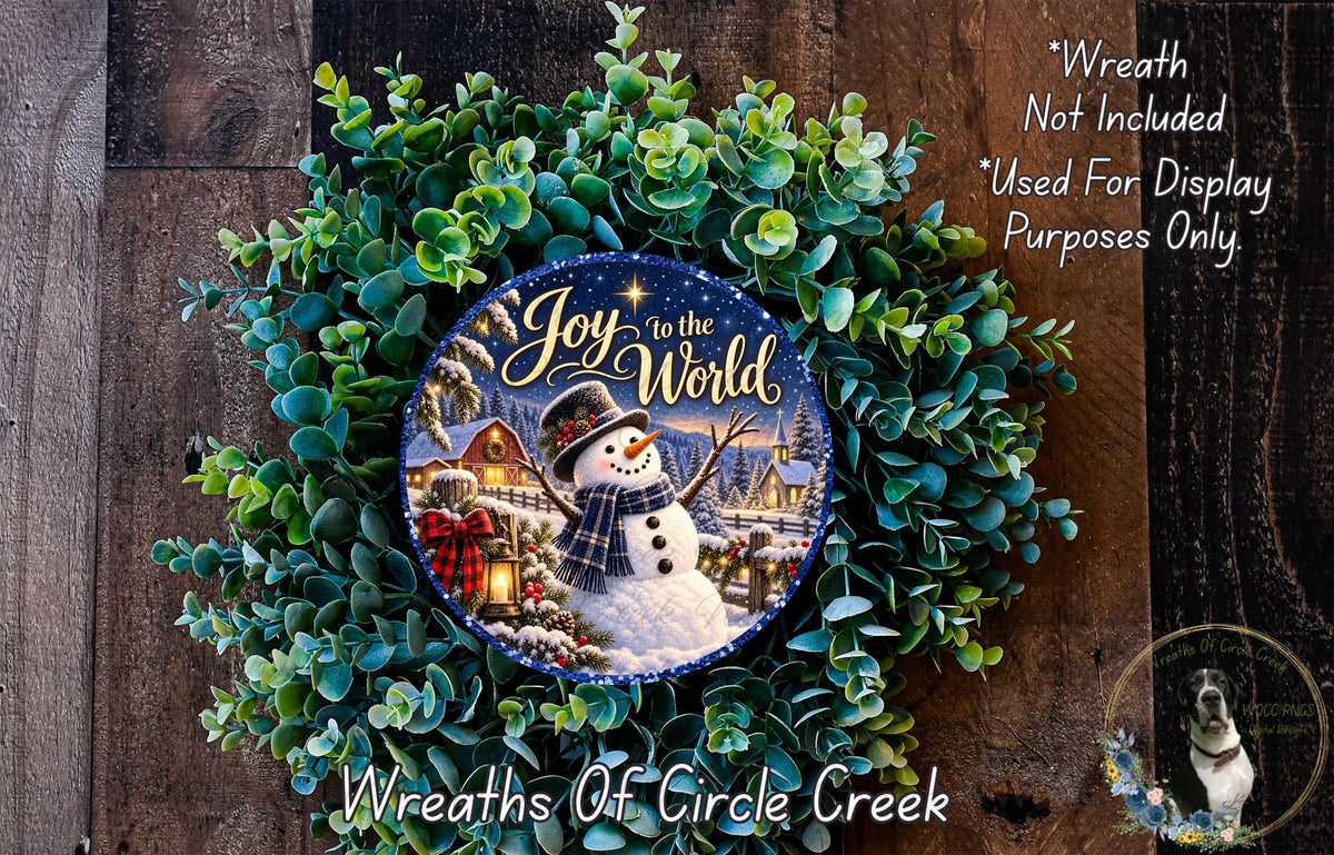 A wreath made of green leaves and a snowman, with a blue and white sign that says "Joy to the World" in the center.